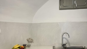 Una cocina con encimera blanca, un lavamanos de acero inoxidable y armarios grises.