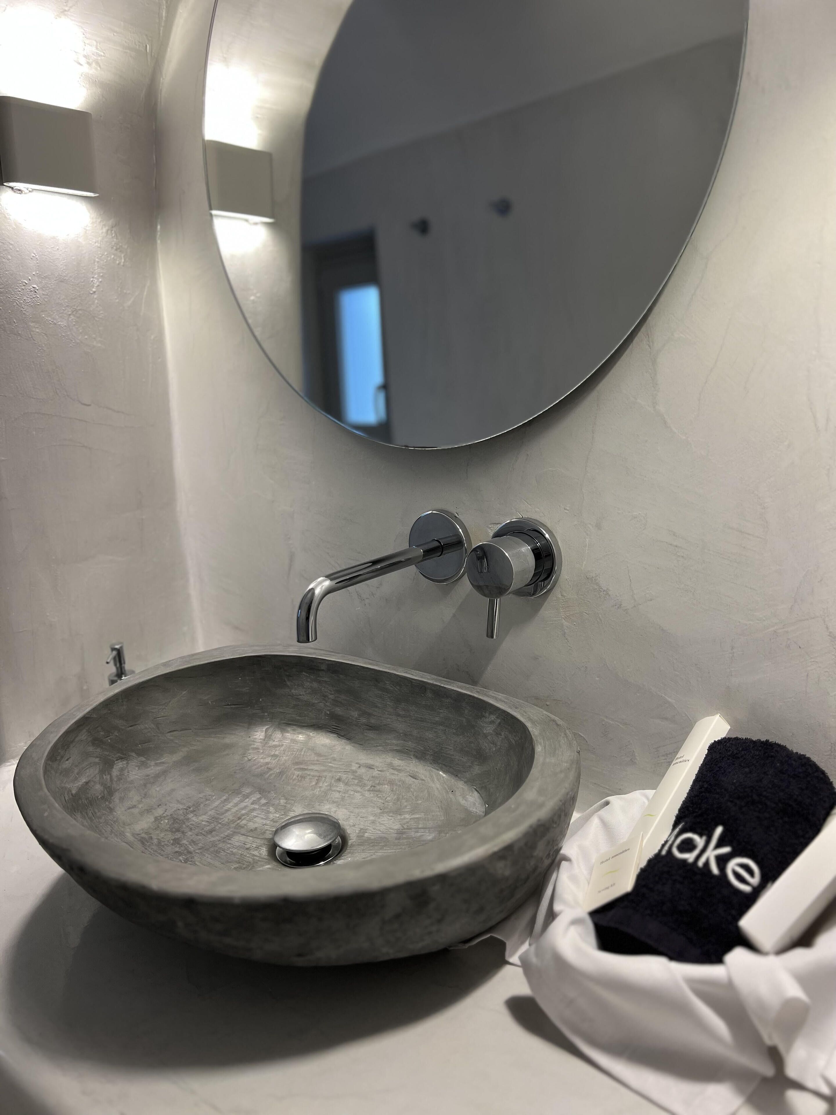 Une salle de bain avec un lavabo rond en métal, un miroir et un porte-serviettes.