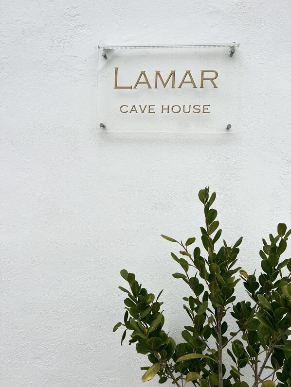 A sign for 'LAMAR CAVE HOUSE' mounted on a white wall.