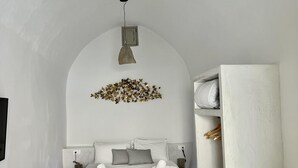 Un dormitorio minimalista con una cama, una lámpara colgante y un estante en la pared.