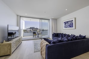 Relax in this stylish living room with a large sofa, flat-screen TV, and city views from the balcony.