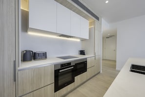 Enjoy cooking in this well-equipped kitchen with oven, dishwasher, and sleek cabinetry.