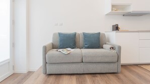 Ein modernes Wohnzimmer mit einem grauen Sofa, zwei blauen Kissen und einer Zeitschrift darauf.