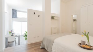 Ein modernes Schlafzimmer mit einem großen Bett, einem Schreibtisch und einem Fenster mit Vorhängen.