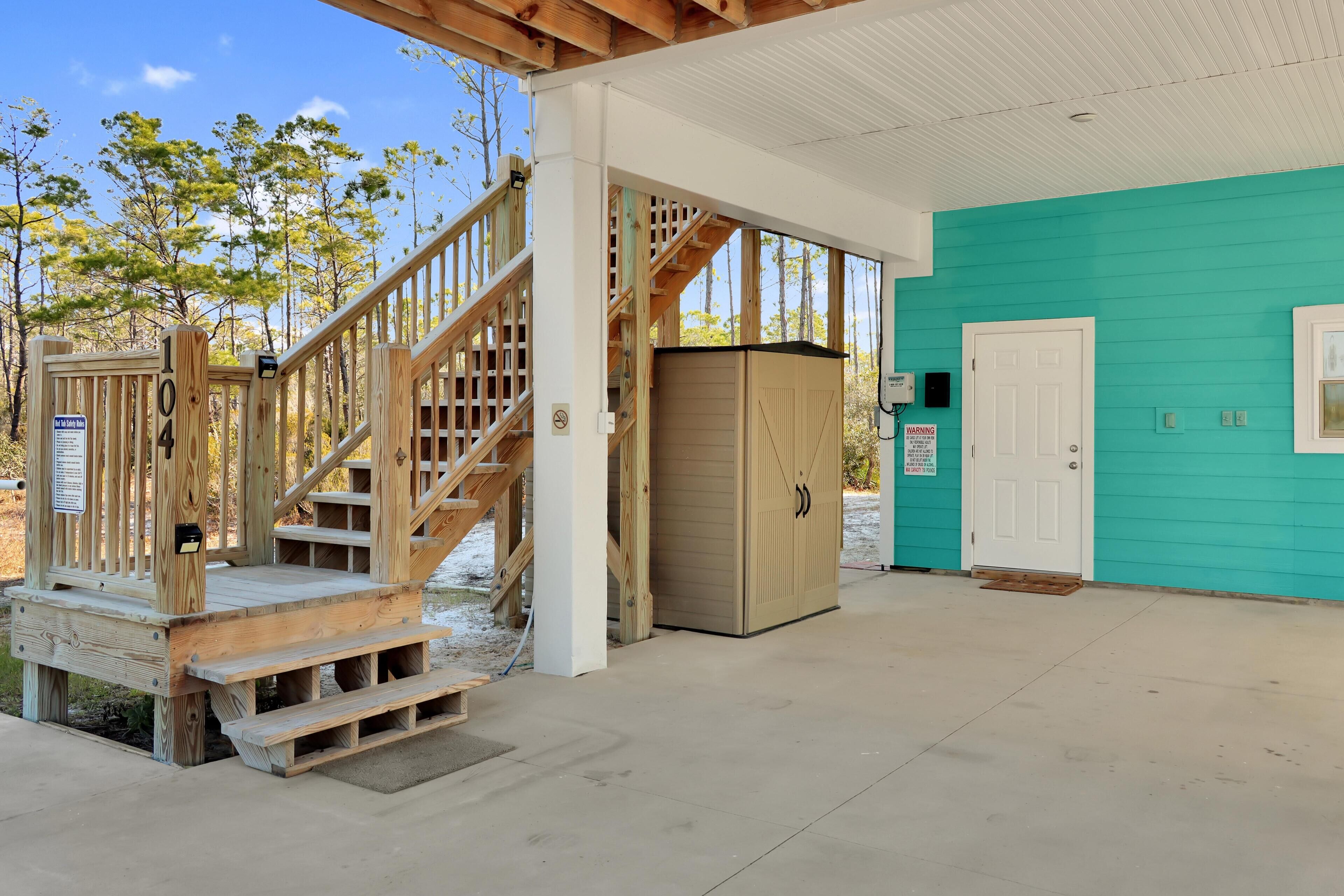 A wooden staircase leading to a covered area with a teal wall and a door.