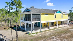 A yellow house with a covered porch, a small deck, and a garage. - Dolphin Daze (Port St. Joe)