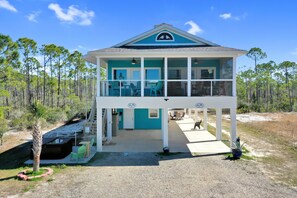 A two-story building with a balcony, a covered porch, and a small outdoor seating area. - Dolphin Daze (Port St. Joe)