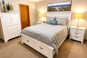 Une chambre à coucher avec un lit, des tables de chevet, une commode et une porte.