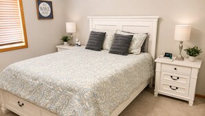 Een slaapkamer met een bed, nachtkastjes, een dressoir en een wandklok.