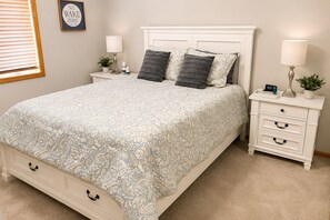 A bedroom with a bed, nightstands, a dresser, and a wall clock.