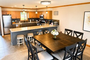A modern kitchen with a central island, stainless steel appliances, and a dining area with a wooden table and chairs.