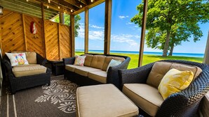 A covered outdoor seating area with wicker furniture and a view of the ocean. - Lakeside Retreat at Izatys - Unit #230 – The Perfect Getaway for All Seasons! (Onamia)