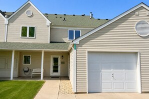 A two-story house with a garage, a covered porch, and a well-maintained lawn.