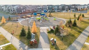 Une aire de jeux avec des toboggans et des structures d’escalade, entourée d’une pelouse et d’arbres.