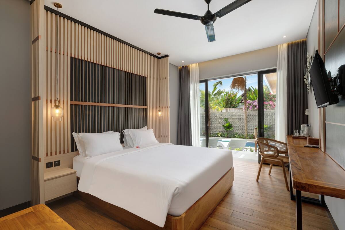 Une chambre d’hôtel moderne, dotée d’un grand lit, d’un bureau et d’un ventilateur de plafond.
