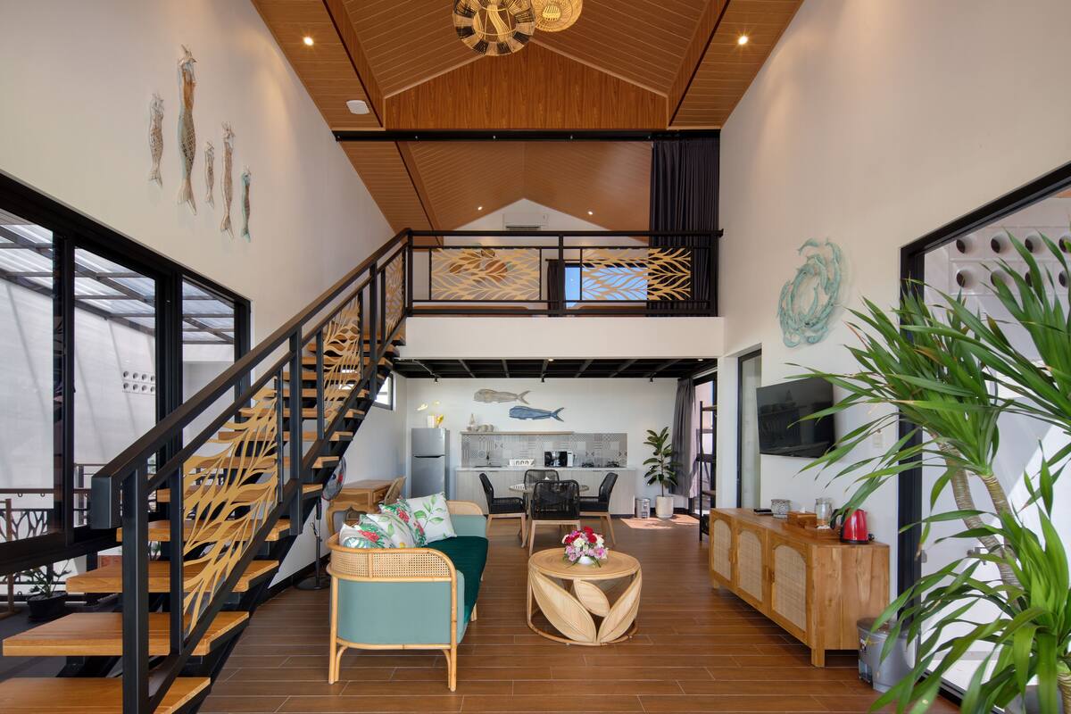 Un vaste espace de vie comprenant un escalier en bois, une cuisine et un coin repas.