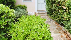 A building with a white door, two windows with shutters, and a stone pathway leading to the entrance. - House for 4 people with air conditioning in a private domain with a pool located in Gassin (GASSIN)