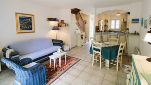 A cozy living room with a sofa, a dining table with chairs, a patterned rug, and a staircase leading to another room. - House for 4 people with air conditioning in a private domain with a pool located in Gassin (GASSIN)