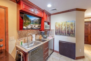 A kitchen with a granite countertop, stainless steel sink, and red cabinetry. - Westgate 3603B (Park City)