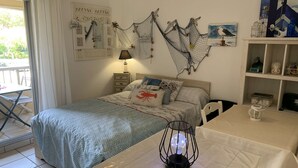 A bedroom with a bed, bedside table, lamp, and wall decorations including nets and a painting. - Studio in Pin Rolland, beach and shops on foot (ST MANDRIER SUR MER)