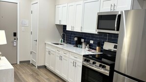 Une cuisine moderne avec des armoires blanches, des appareils en acier inoxydable et un plancher en bois.