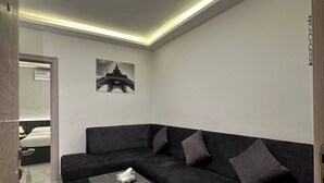 Ein modernes Wohnzimmer mit einem Ecksofa, einem Couchtisch und einer Deckenleuchte.