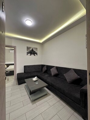 A modern living room with a sectional sofa, a coffee table, and a ceiling light.