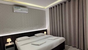 Ein modernes Hotelzimmer mit einem großen Bett, Nachttischen, einer Klimaanlage und einer Deckenleuchte.