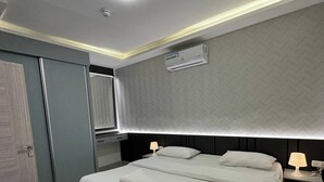 Ein modernes Schlafzimmer mit einem großen Bett, Nachttischlampen, einer Deckenleuchte und einer Klimaanlage.