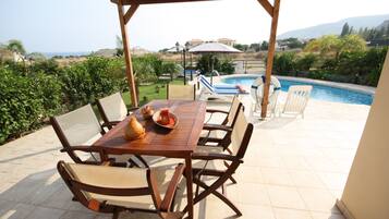 Un patio cubierto con piscina, mobiliario exterior y vistas del paisaje.