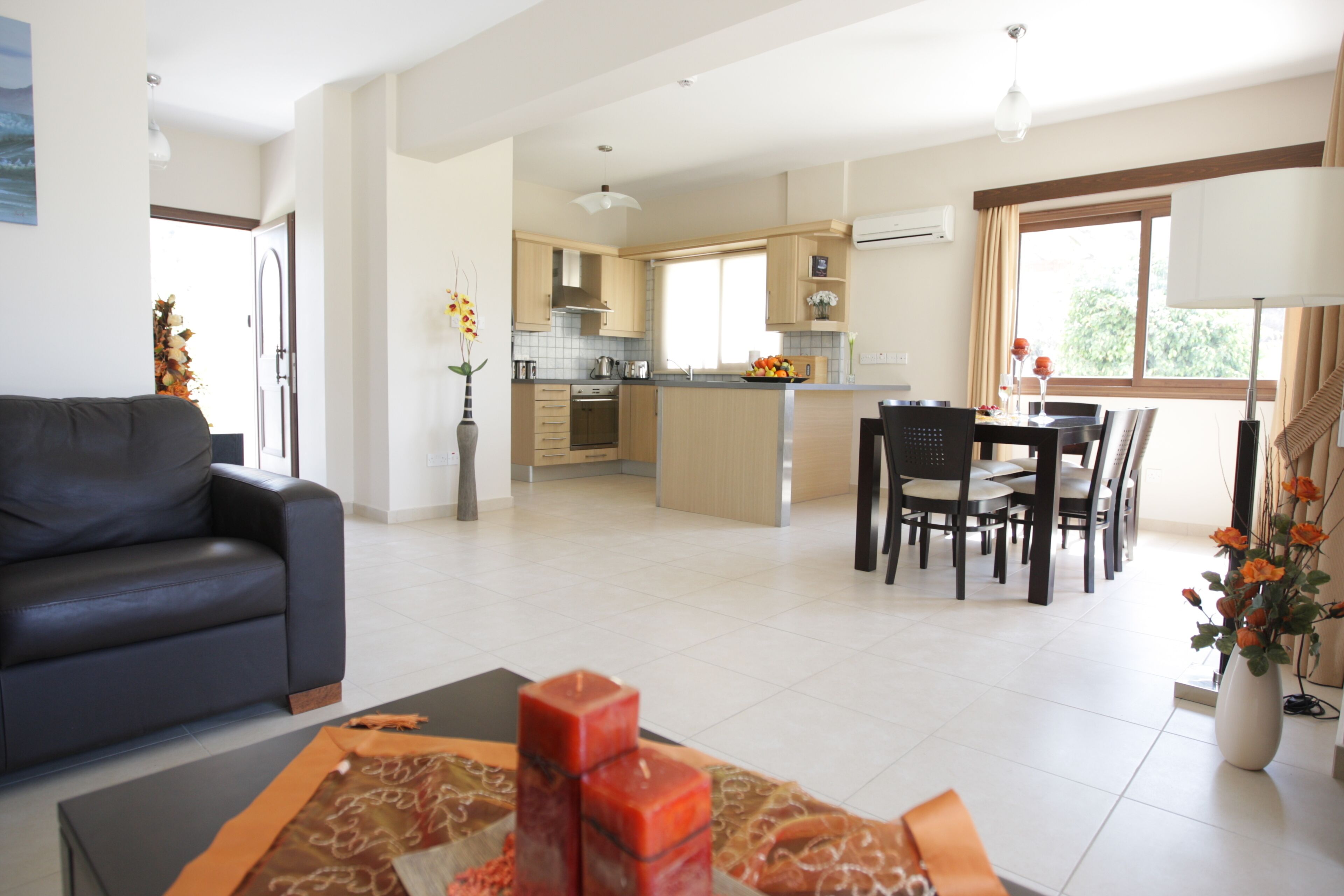 Una sala moderna con sofá, comedor con mesa y sillas, y cocina con armarios y electrodomésticos.