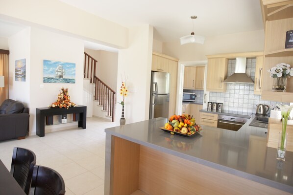 A modern kitchen with a central island, stainless steel appliances, and wooden cabinetry.