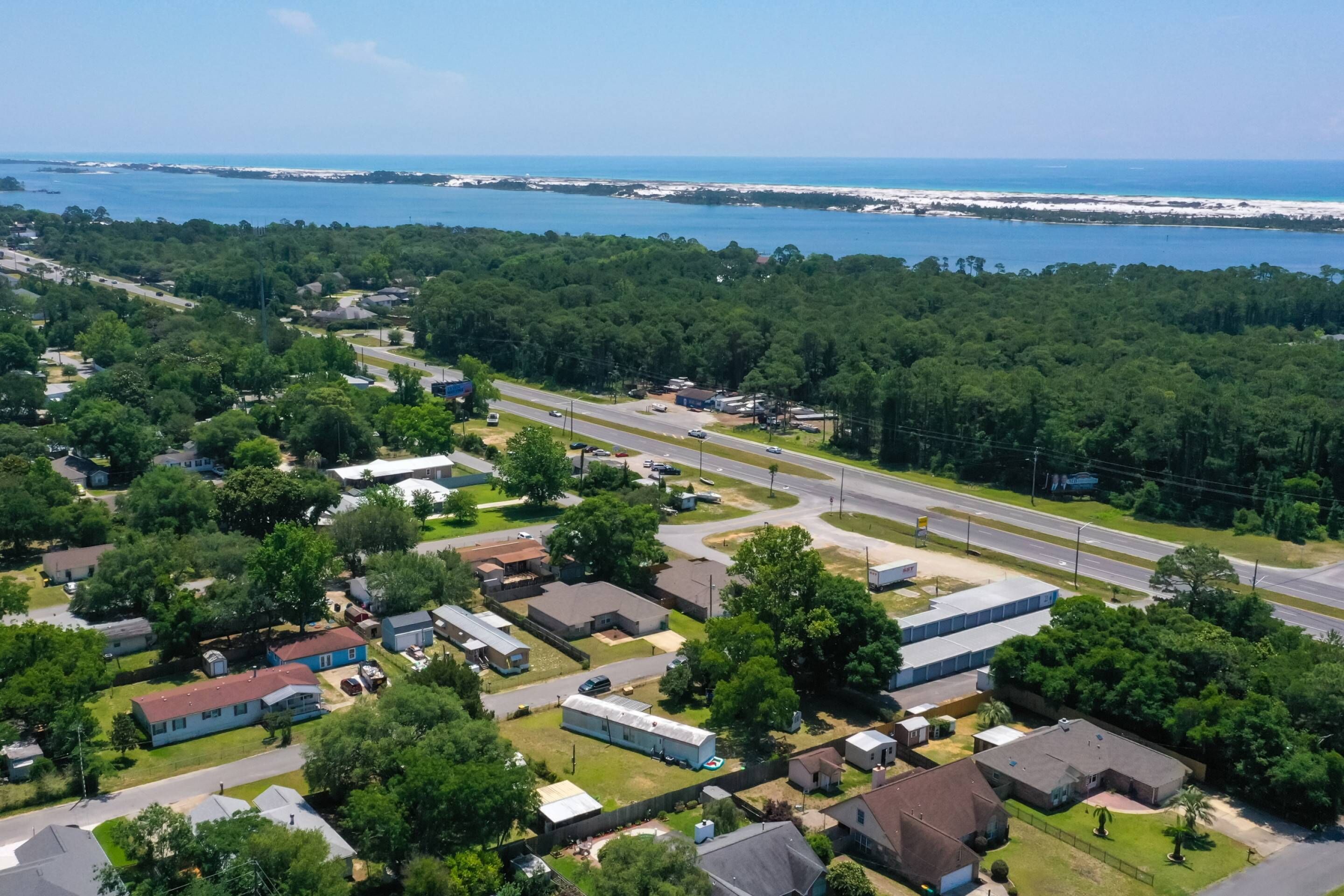 An aerial view of a residential area with houses, roads, and a beach in the background.