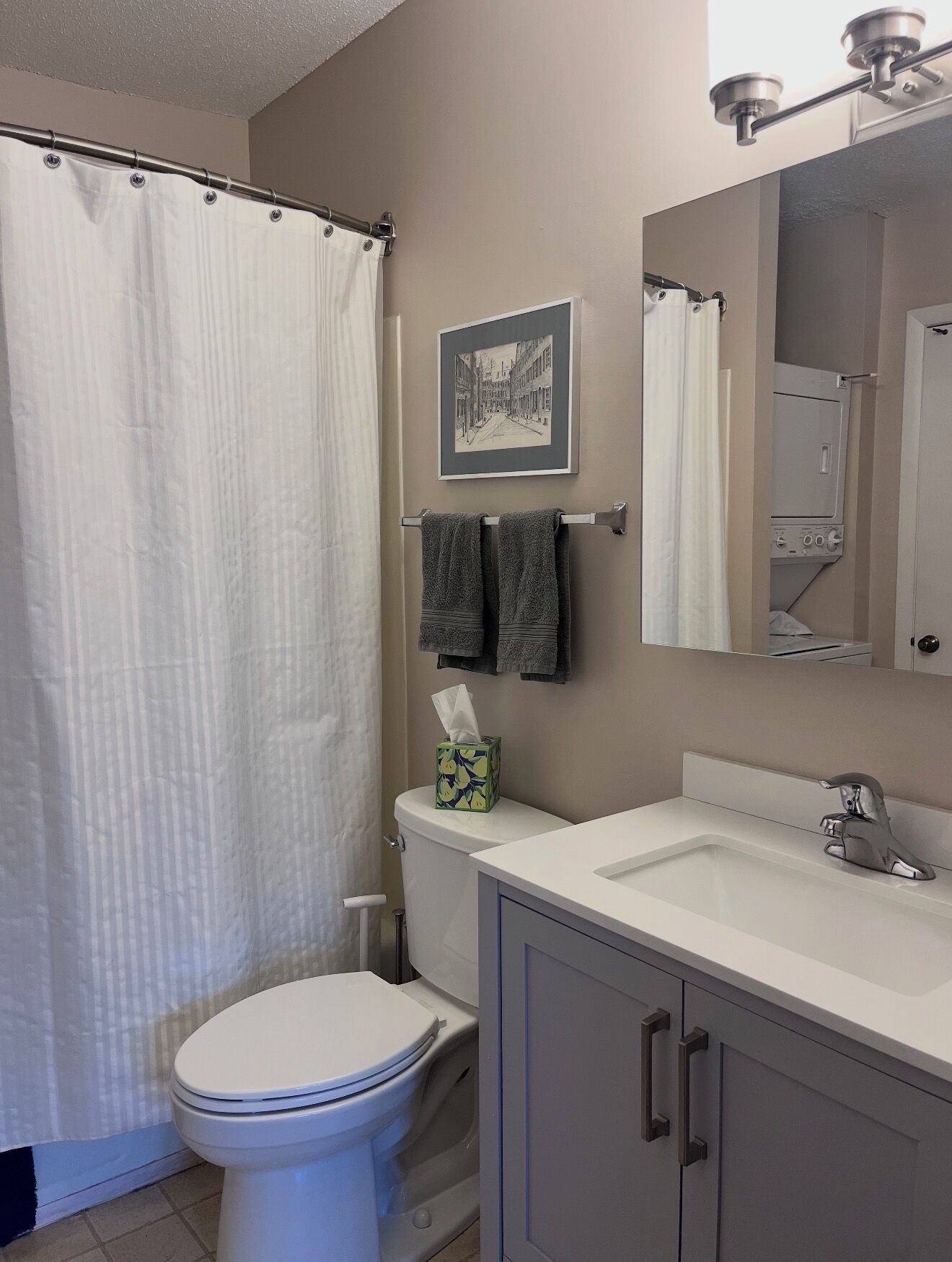 A bathroom with a toilet, a sink, a mirror, a towel rack, and a shower curtain.