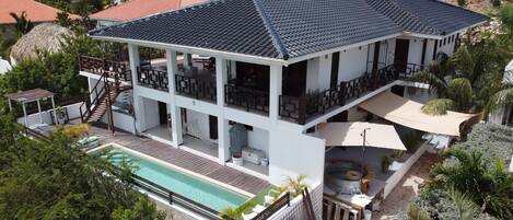 Ein mehrgeschossiges Haus mit Swimmingpool, Außenbereich und einer großen Terrasse.
