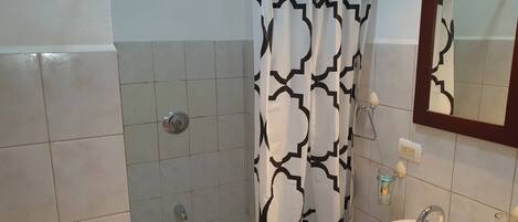 A bathroom with a shower, a sink, a mirror, and a towel rack.