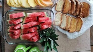 A table with various food items including pineapple slices, melon chunks, apple slices, watermelon pieces, and bread. - Room-standard Queen Room two Beds n01 (Santa María Colotepec)