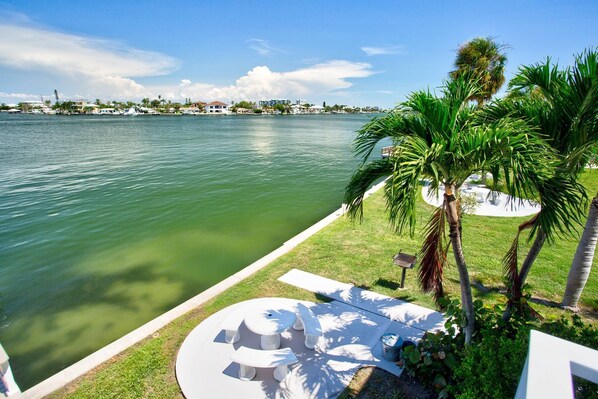 A waterfront property with a pool, palm trees, and a view of the water. - Waterfront Condo with Day-use Dock. Water View & Short Walk to Beach. Near Restaurants and Shopping. (Treasure Island)