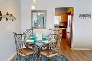 Un coin repas avec une table en verre, des chaises en métal et un motif décoratif représentant un poisson sur le mur.
