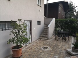 A courtyard with a potted plant, a staircase, and a table with chairs.
