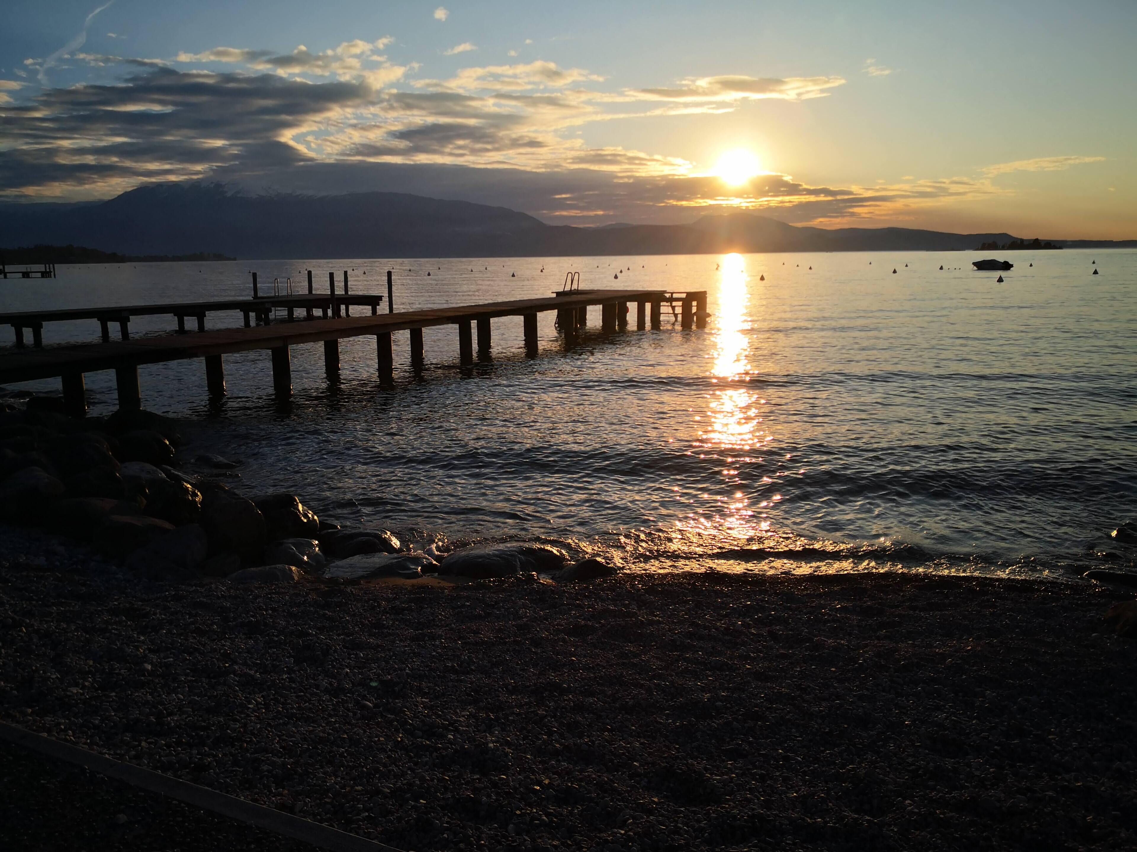 A sunset over a calm lake with a pier extending into the water.