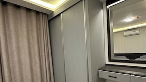 Ein Zimmer mit Holzboden, einem grauen Kleiderschrank, einem Spiegel und einer Deckenleuchte.