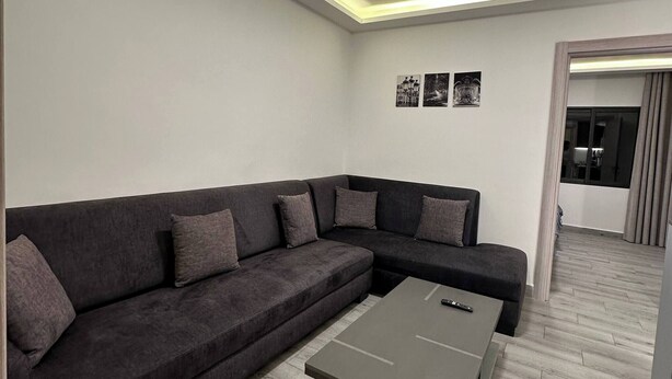 Ein modernes Wohnzimmer mit Ecksofa, Couchtisch und einer eingelassenen Deckenleuchte.