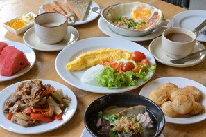 A table with various breakfast items including eggs, toast, watermelon, and a salad. - Rattana Park Hotel (Phitsanulok)