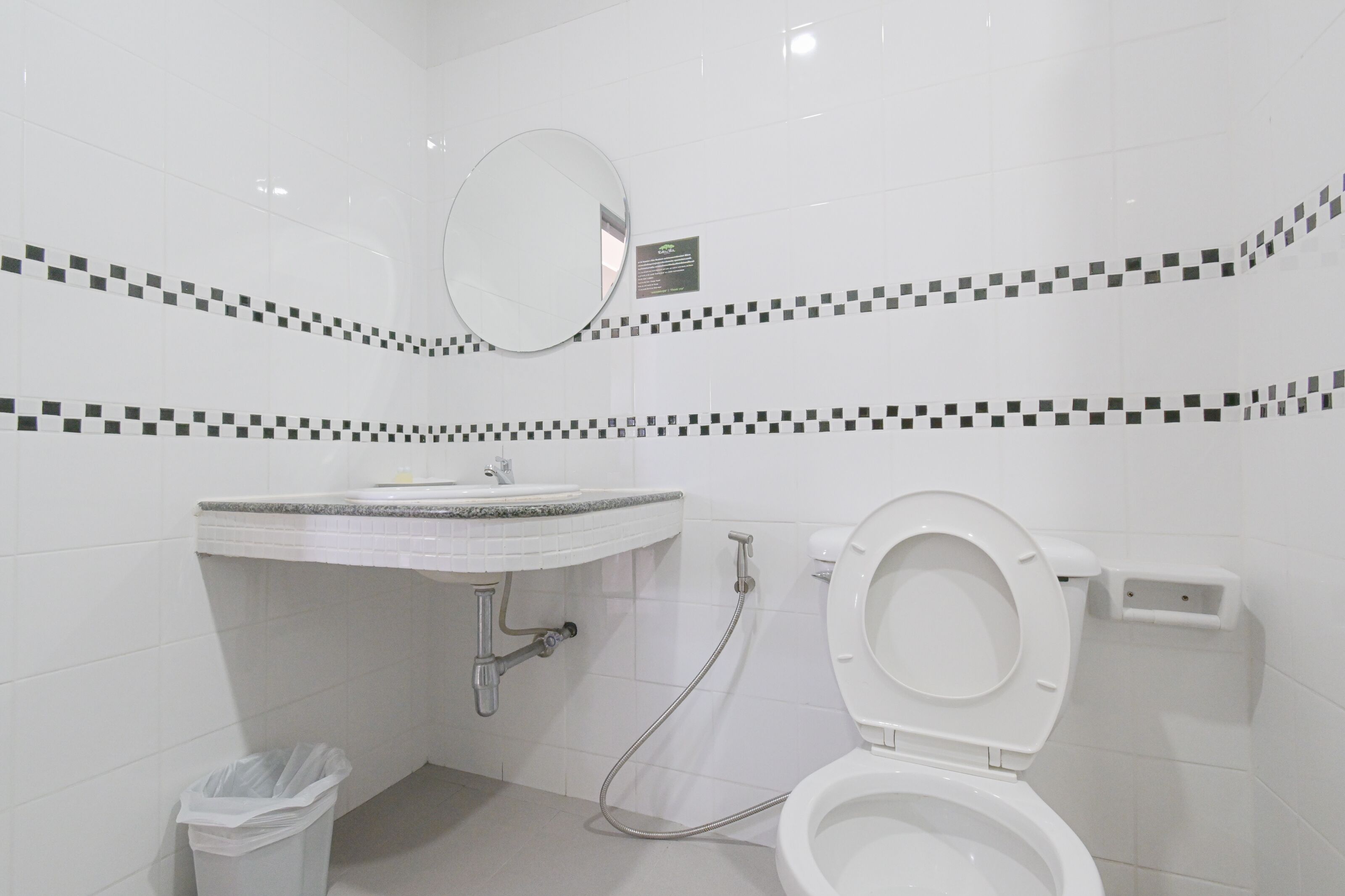 Um banheiro moderno com pia branca, espelho e vaso sanitário.