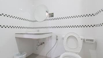 Um banheiro moderno com pia branca, espelho e vaso sanitário.