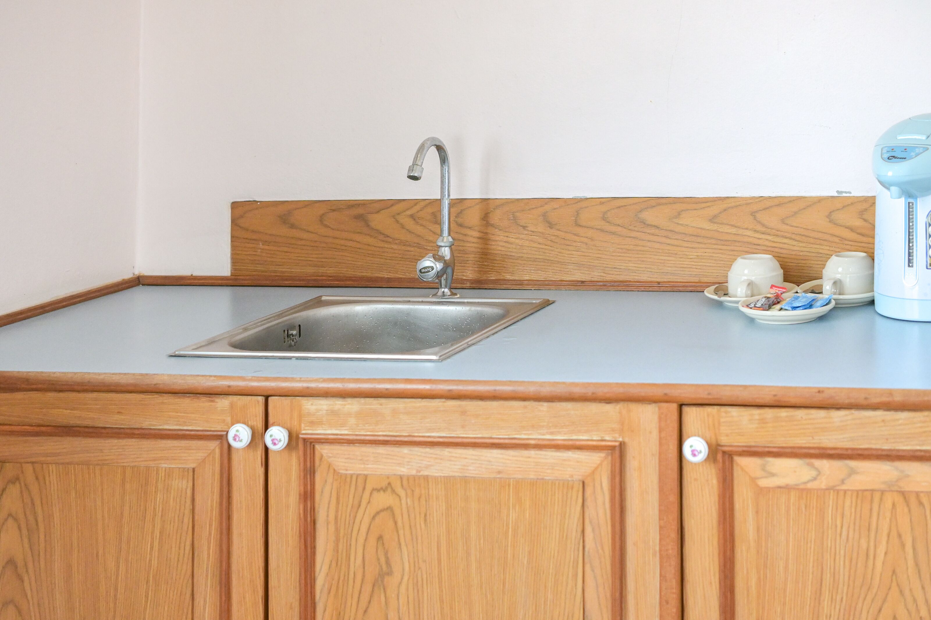 A kitchen with a stainless steel sink, wooden cabinets, and a coffee maker on the countertop.