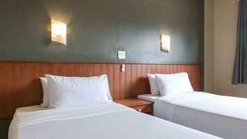 Habitación de hotel con dos camas individuales, cabecero de madera y dos lámparas fijadas a la pared.