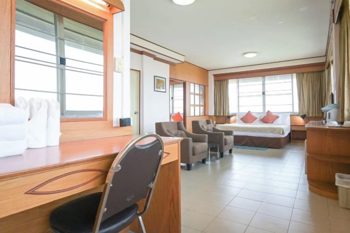 A hotel room with a bed, a desk, a chair, and a sofa.