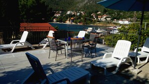 A terrace with outdoor seating, a view of a coastal town, and a mountain backdrop. - Getaway Seaside Sweet (Dubrovnik)